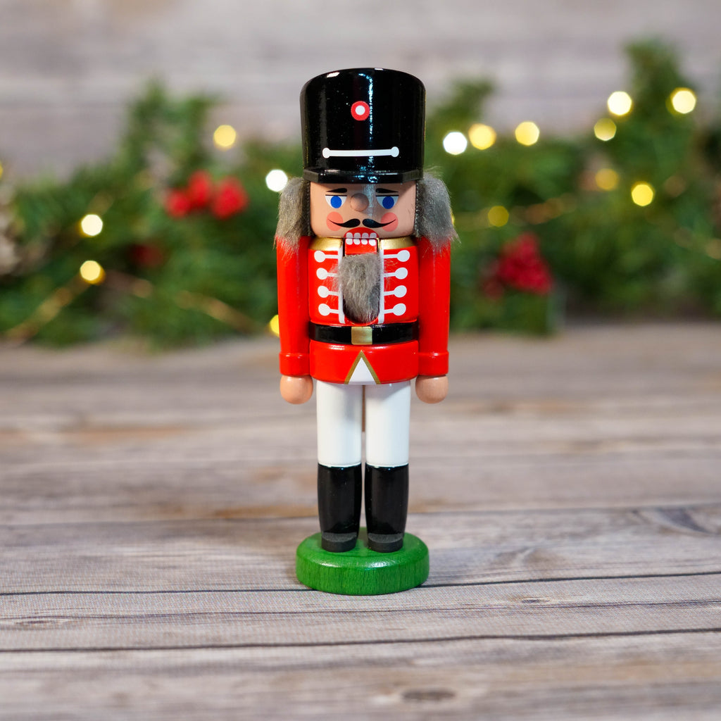 Mini Red Hussar Nutcracker with Black Hat and Gold Trim in Festive Background
