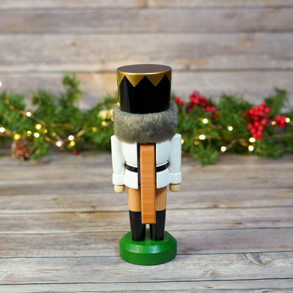 Nutcracker King standing by wooden background with festive lights