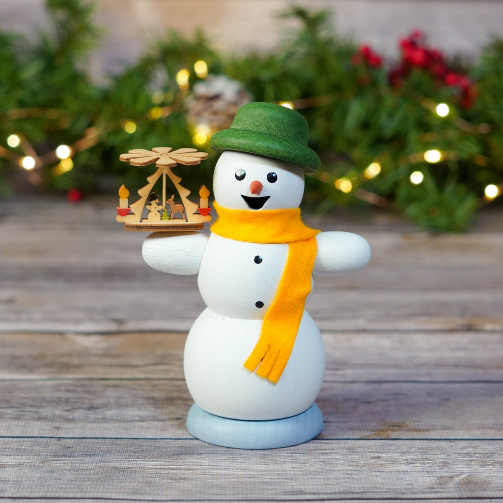 Snowman smoker with Christmas pyramid on a wooden table with festive background