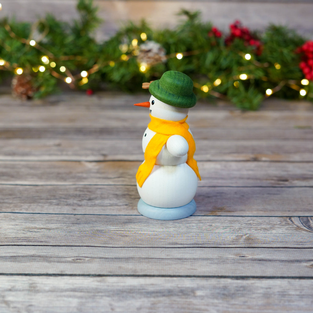 Close-up of snowman holding a tiny Christmas pyramid