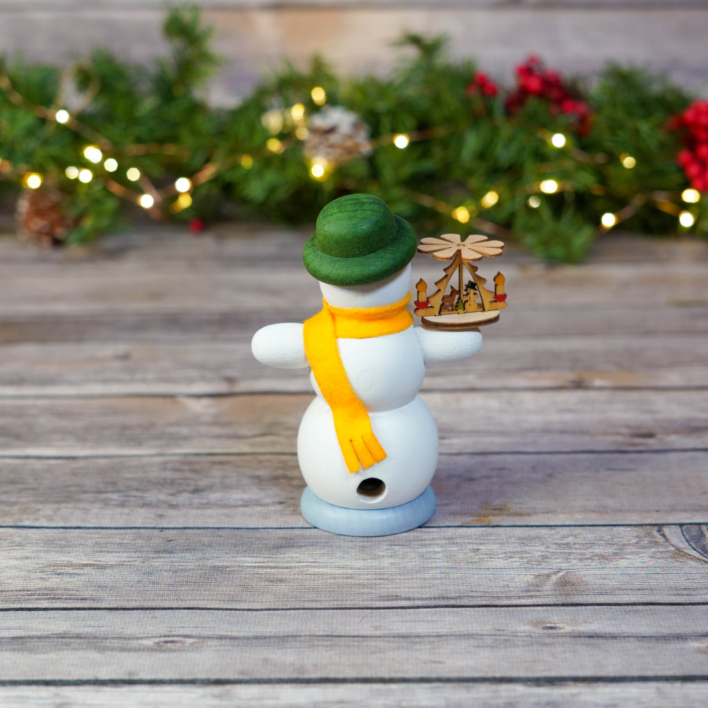 Snowman with green hat and orange scarf in festive setting