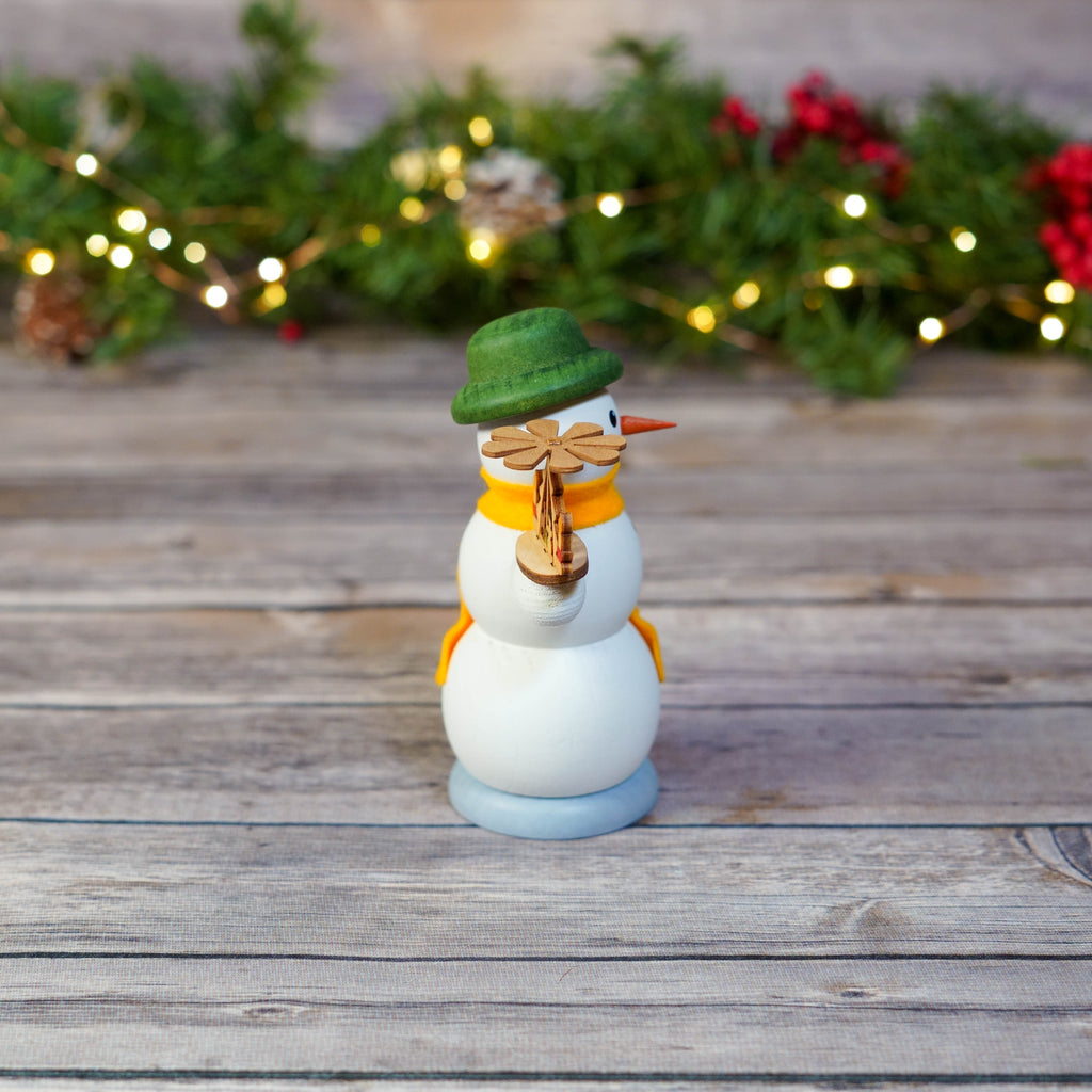 Traditional German snowman with pyramid illuminated by holiday lights