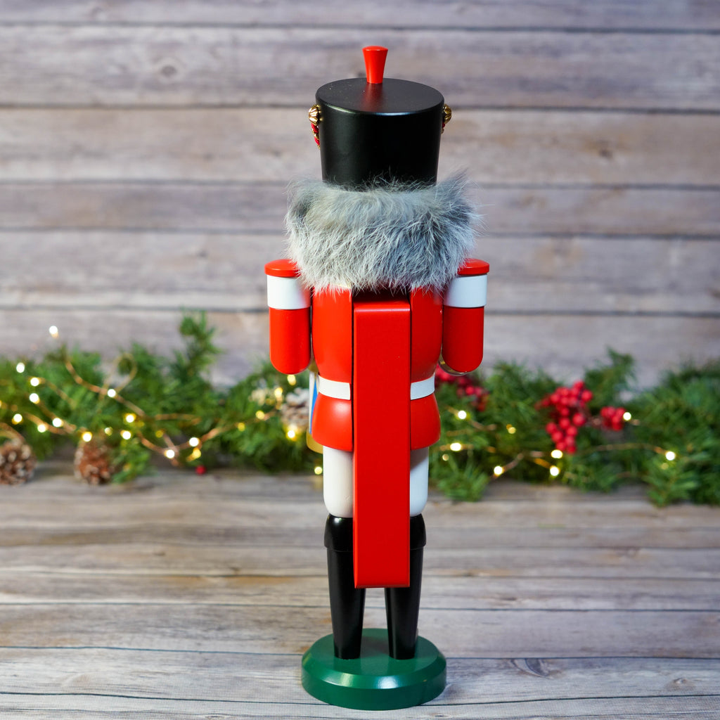 Red and black drummer nutcracker with a fur hat on wooden background