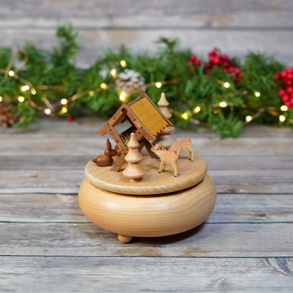 Close-up of a wooden music box showing detailed deer and forest setting