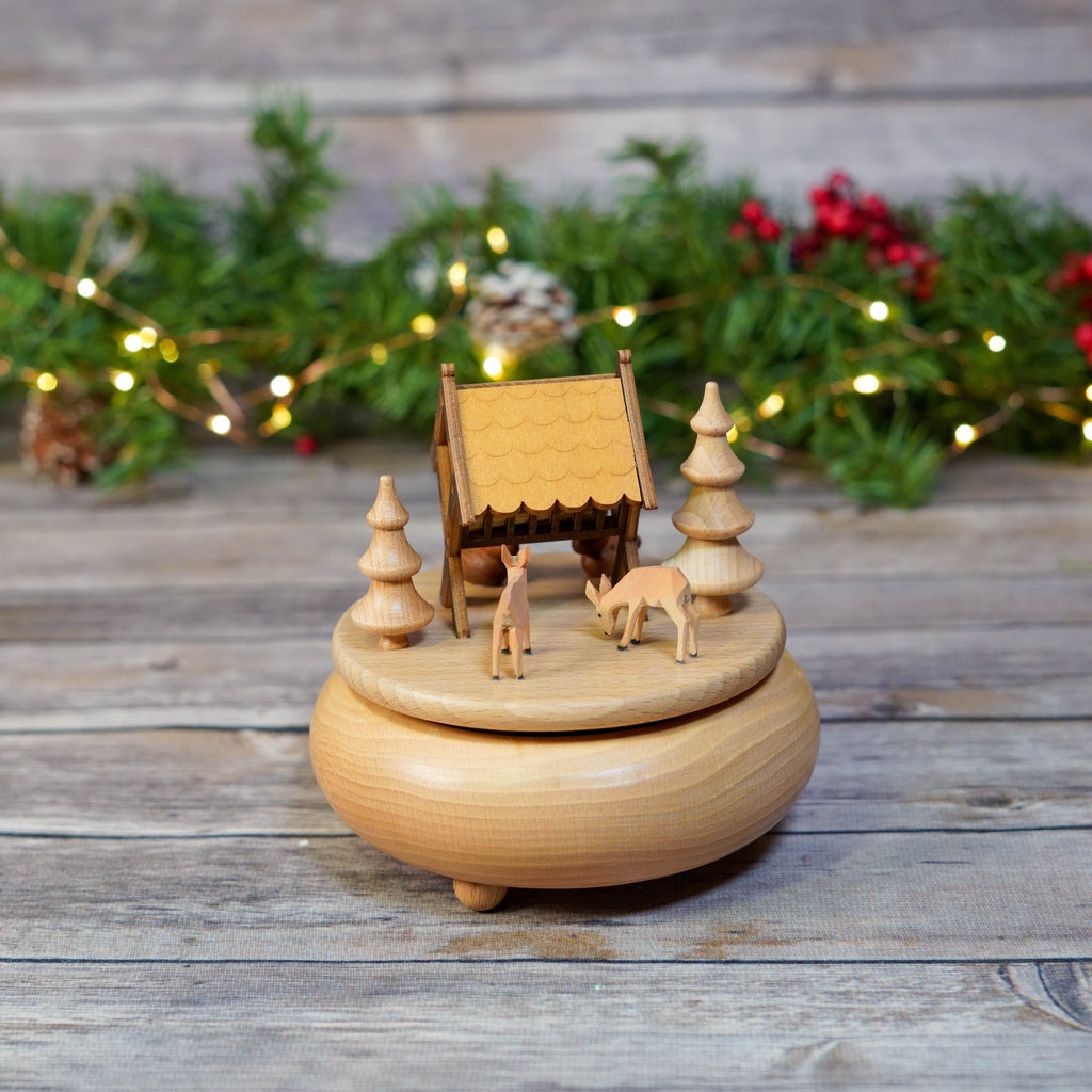 Handcrafted wooden music box with deer and trees on a festive background