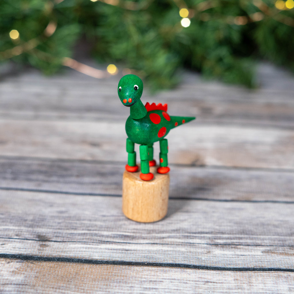 Green and red wooden dinosaur toy on wooden base